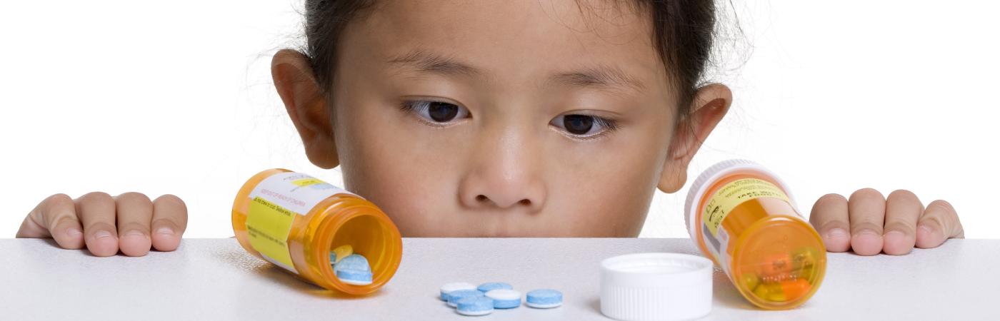 childlookingatprescriptionbottlesontable