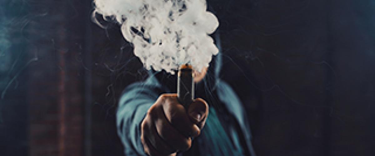 person holding vape pen with smoke coming out of it