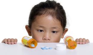 childlookingatprescriptionbottlesontable