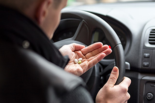 man with pills behind the wheel